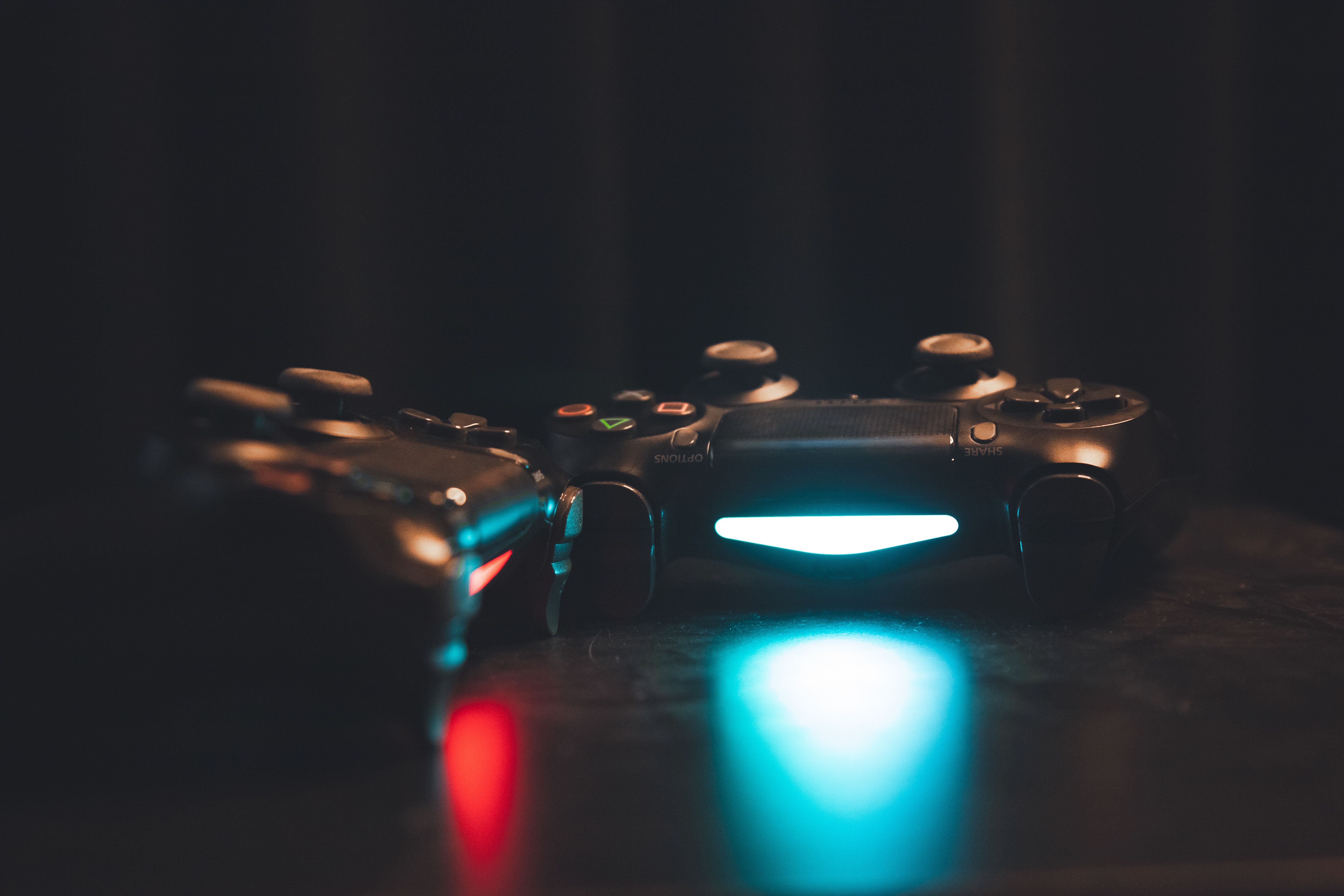 Two glowing PlayStation controllers on a dark surface